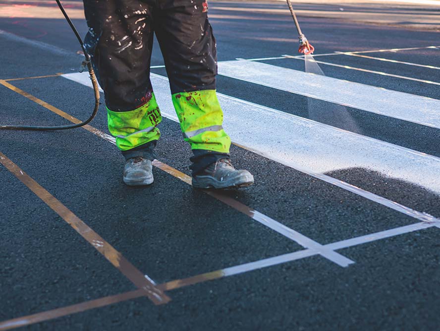 person painting stripes in a parking lot