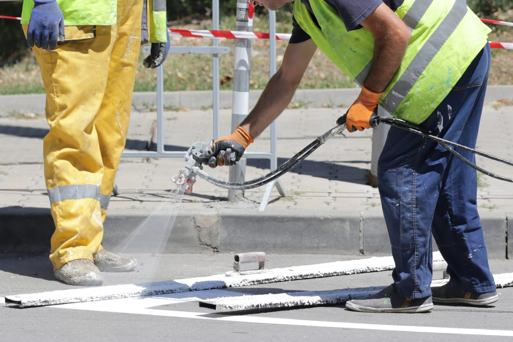 Workers paint parking lot stripes on new asphalt
